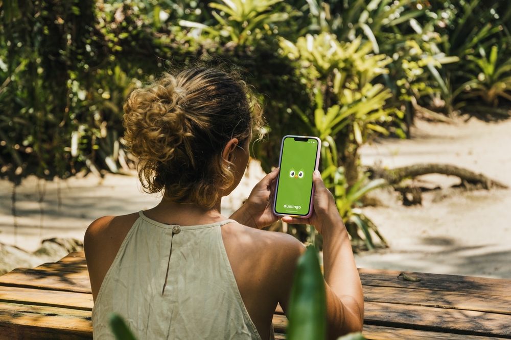 Eine Frau hält die Flaggen der Sprachen hoch, welche sie mit Hilfe von Duolingo lernt.