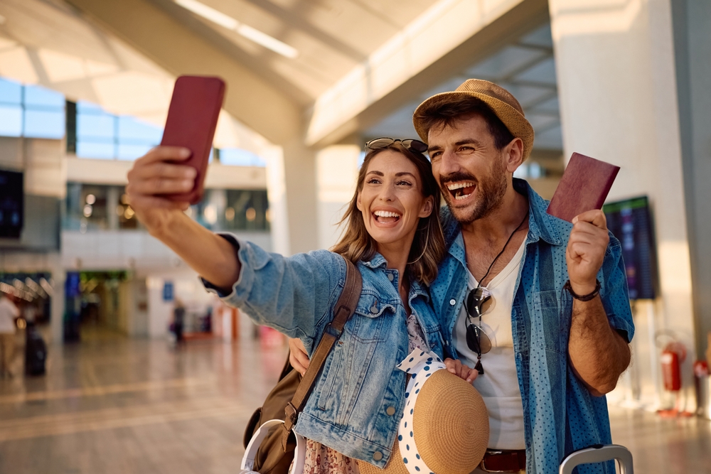 Ein Pärchen hält am Flughafen stolz seine Reisepässe hoch.